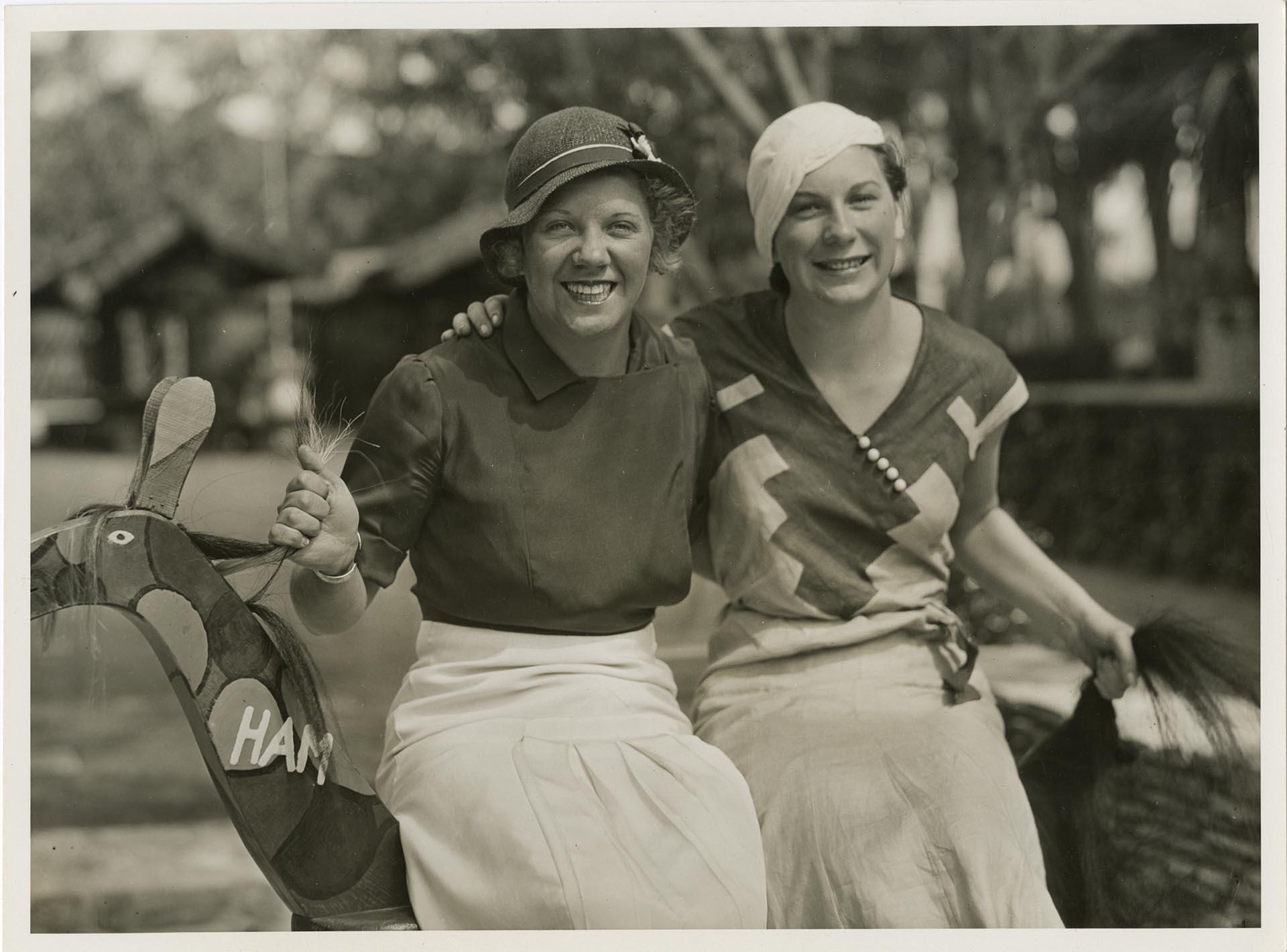 Image of Olympians Helene Madison and Georgia Coleman in street clothes sitting on wooden horse, Los Angeles, 1932