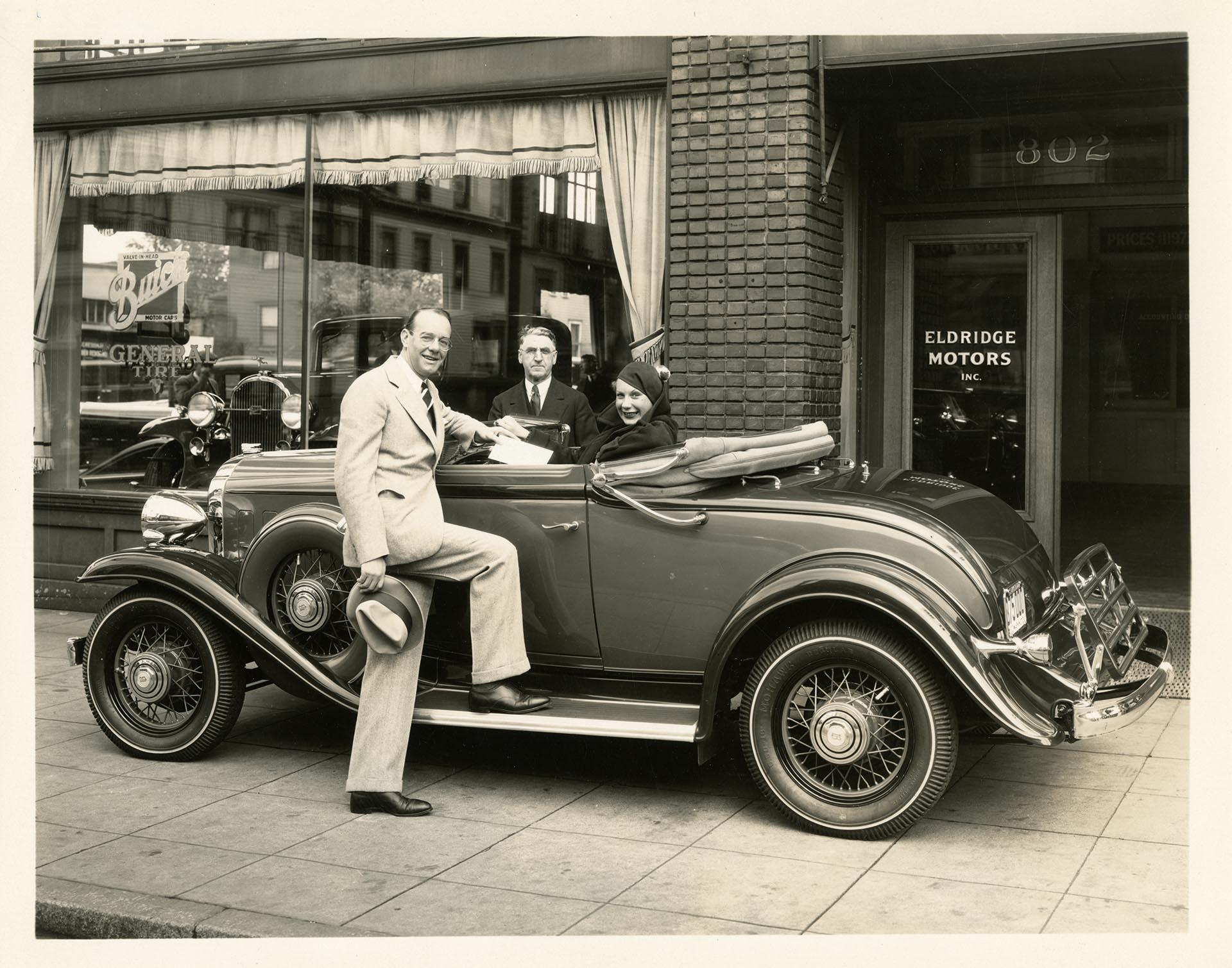 Image of Helene Madison and two men near car in front of Eldridge Buick, Pike Street, Seattle, September 1932