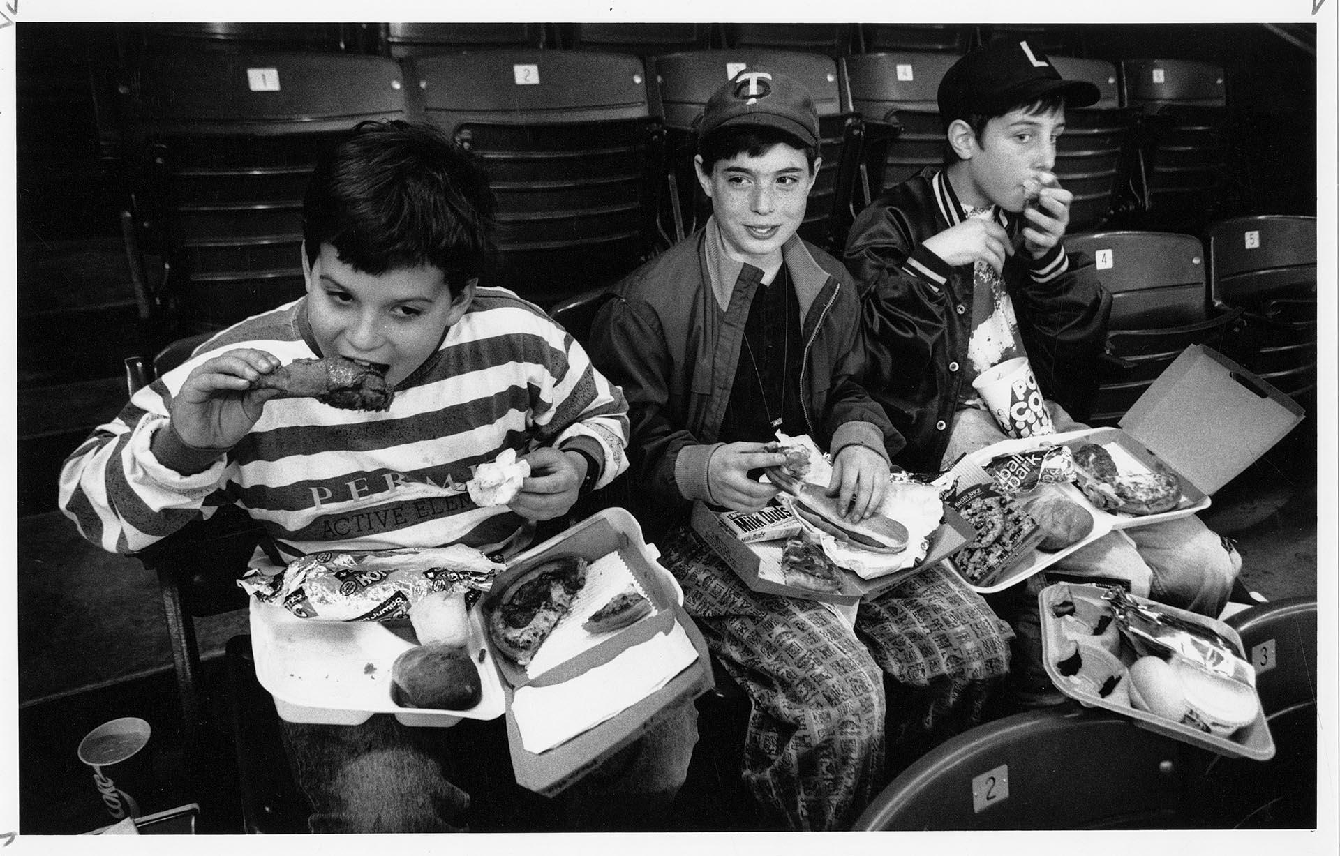 Image of Three young Mariners fans tasting new vendor offerings at Kingdome, April 8, 1991
