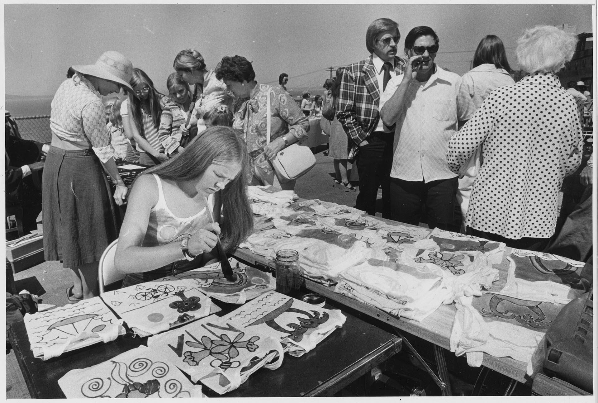 Image of Woman painting t-shirts at Pike Place Market, July 16, 1976