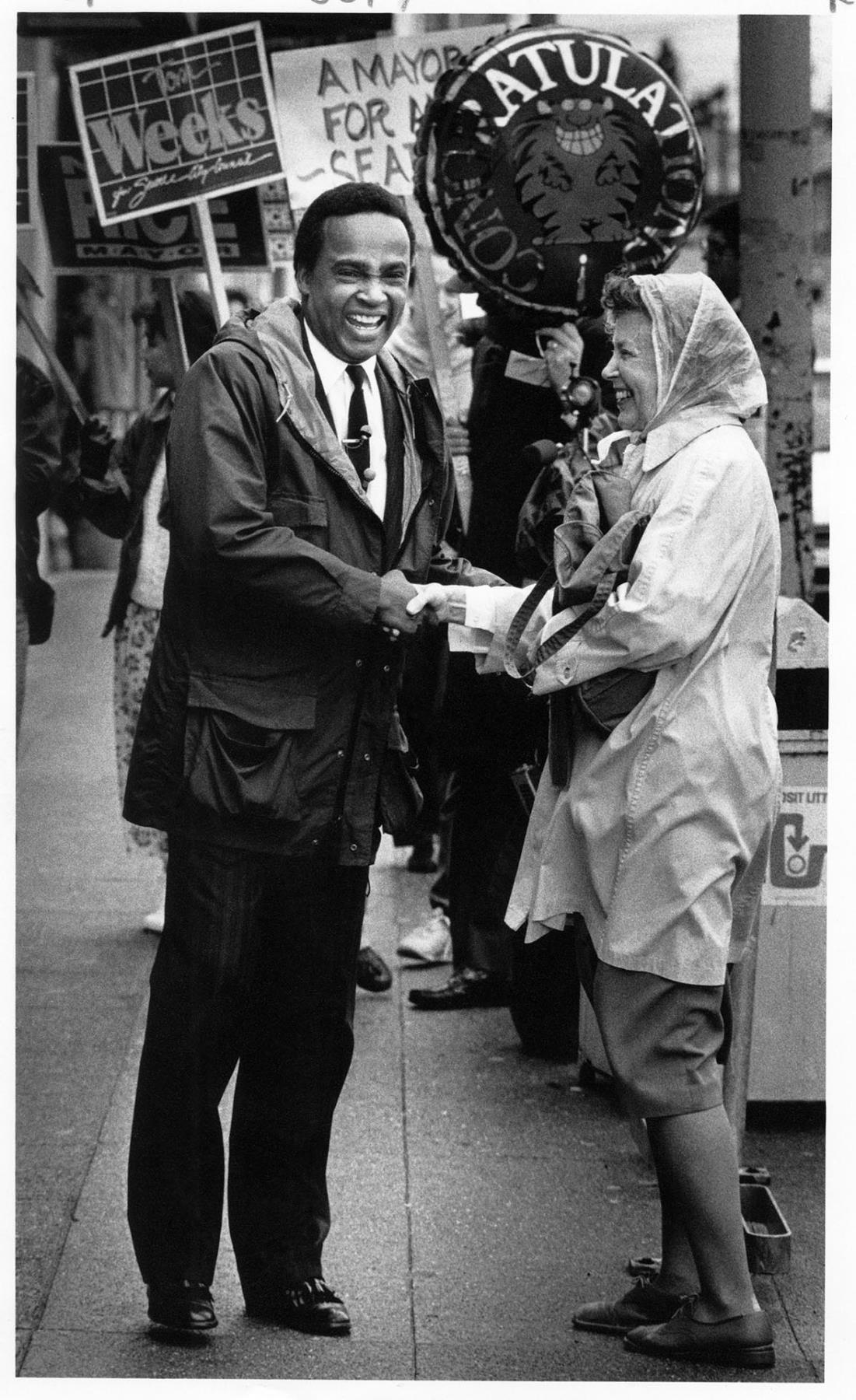 Image of Norm Rice shaking woman's hand on California Ave., West Seattle, November 8, 1989