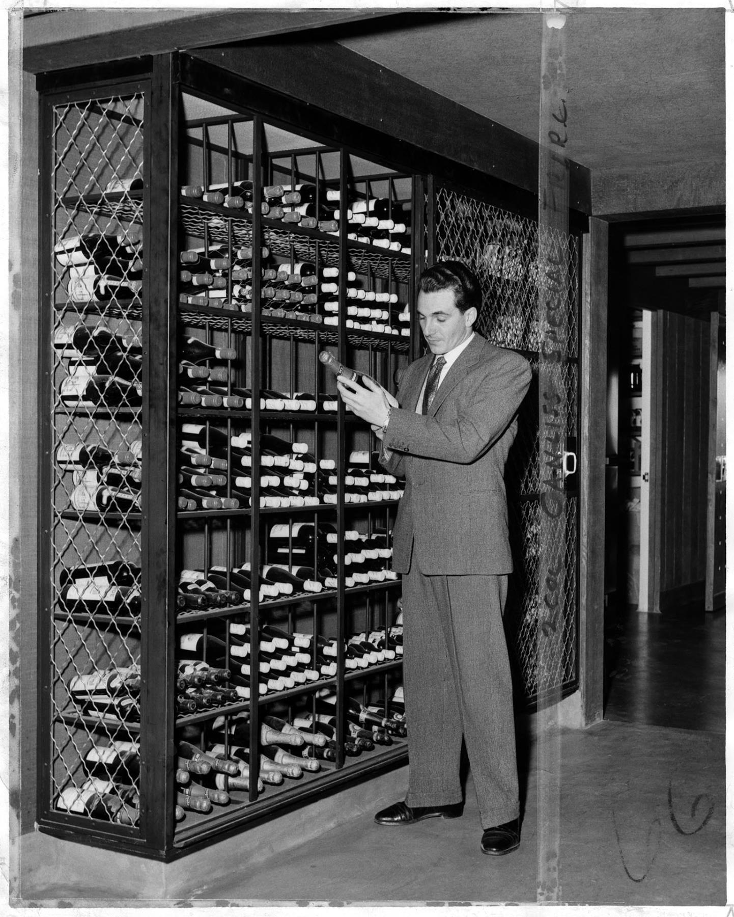 Image of Rudy Valiani inspecting wine in wine cellar at Canlis, Seattle, March 28, 1958