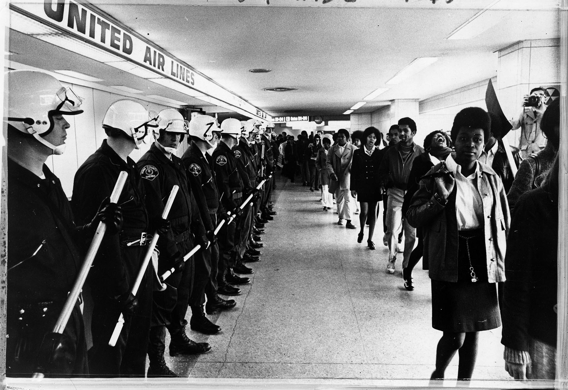 Image of King County Sheriff officers watching CCA demonstrators at Sea-Tac airport, November 6, 1969