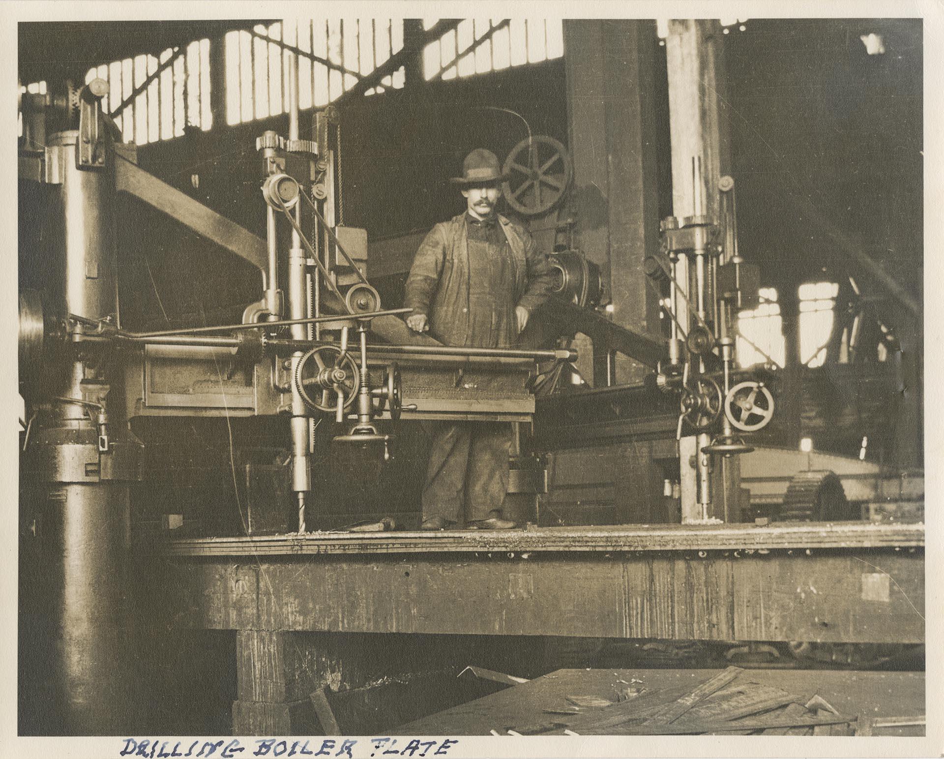 Image of Moran Brothers Company employee with drill at the shipyard on Western Avenue, Seattle, circa 1900