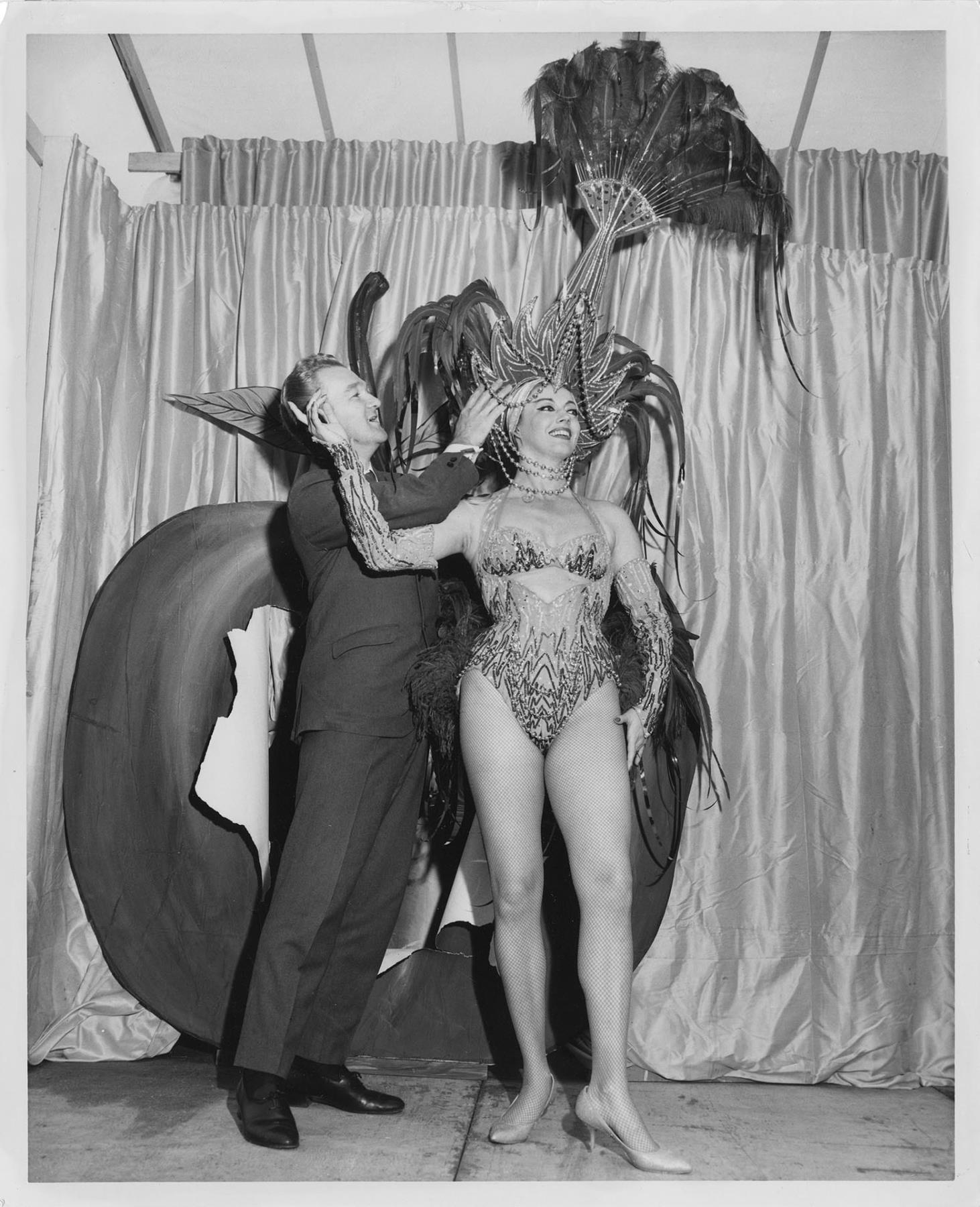 Image of John Eaton adjusting headpiece on model Donna Rydberg, 1961