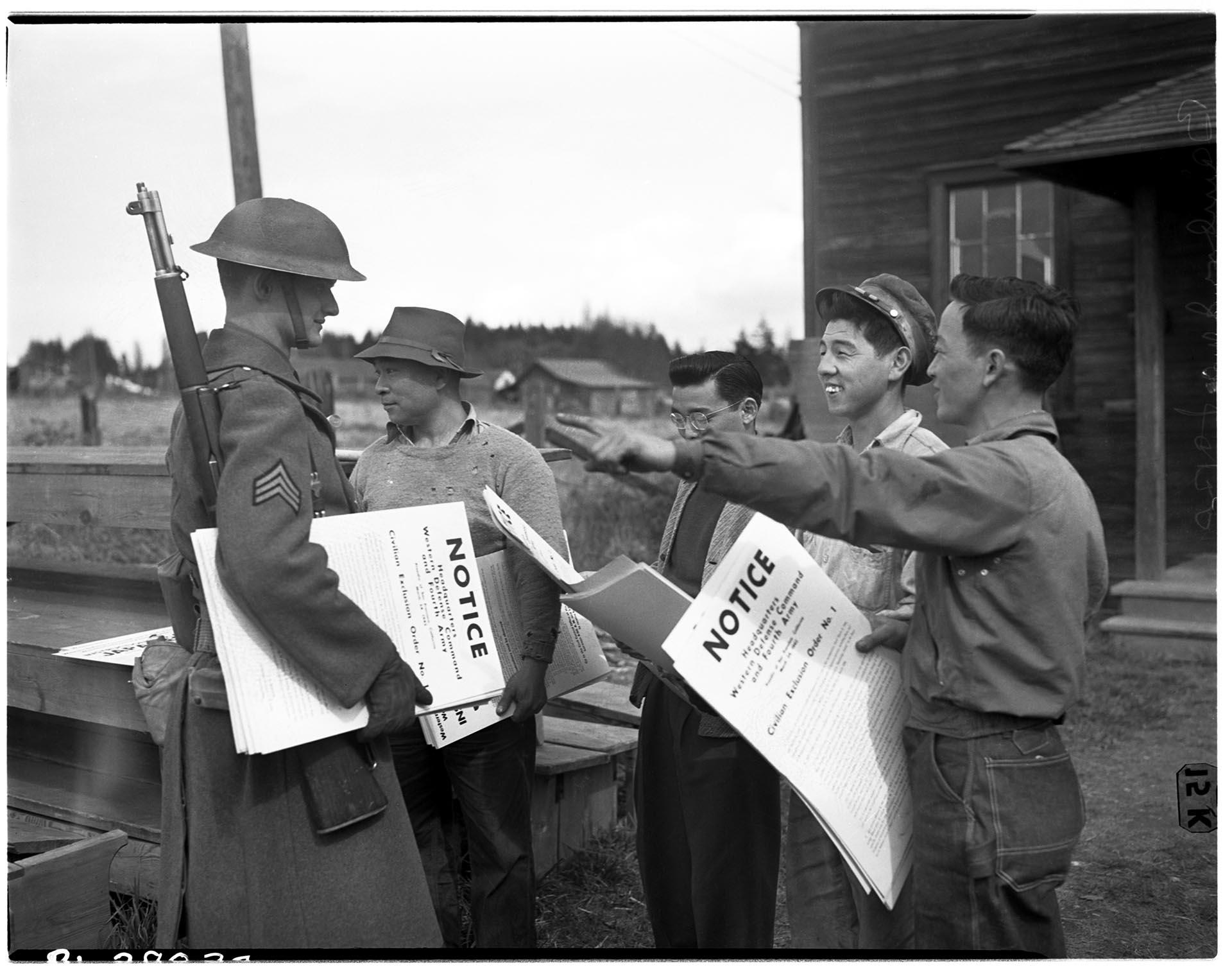 Image of U. S. Army soldier and Japanese Americans with forced removal order, Bainbridge Island, March 25, 1942