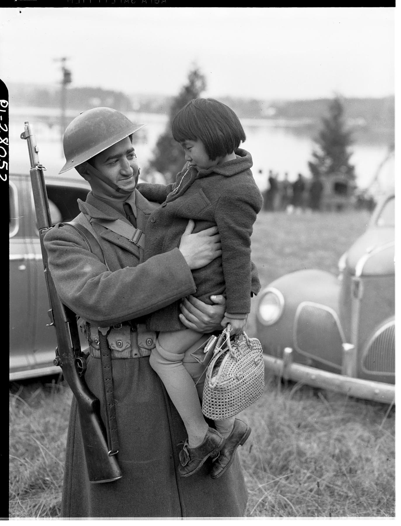 Image of U. S. soldier holding Japanese American girl during forced removal, Bainbridge Island, March 30, 1942