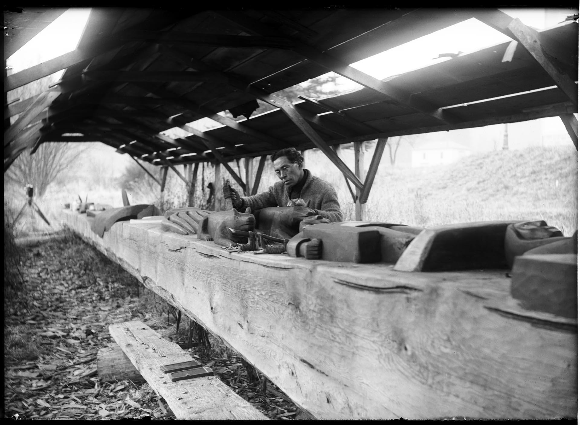 Image of William Shelton carving a story pole, circa 1920