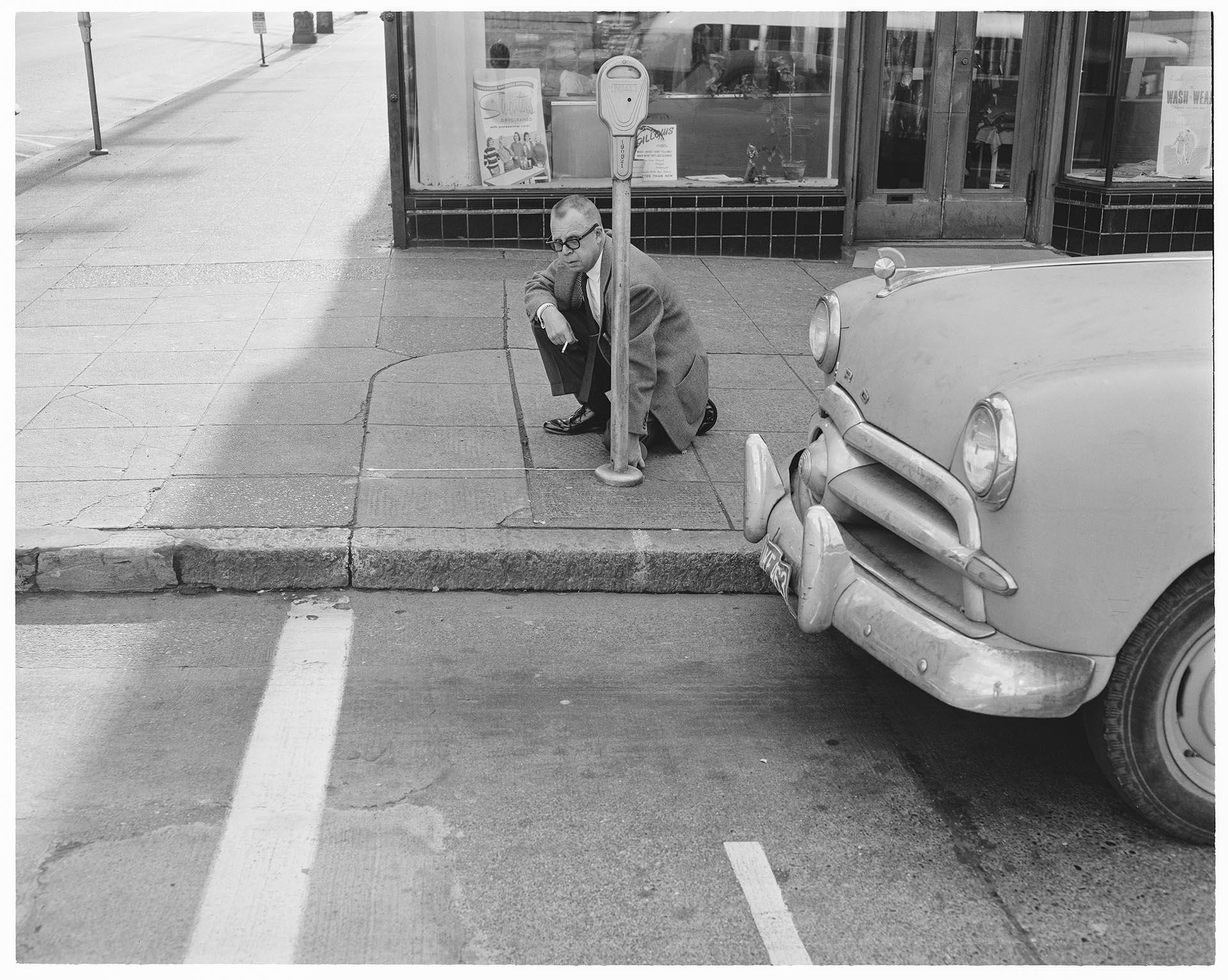 Image of Reporter Jack Jarvis measuring distance from parking meter to crosswalk, Seattle, October 1961
