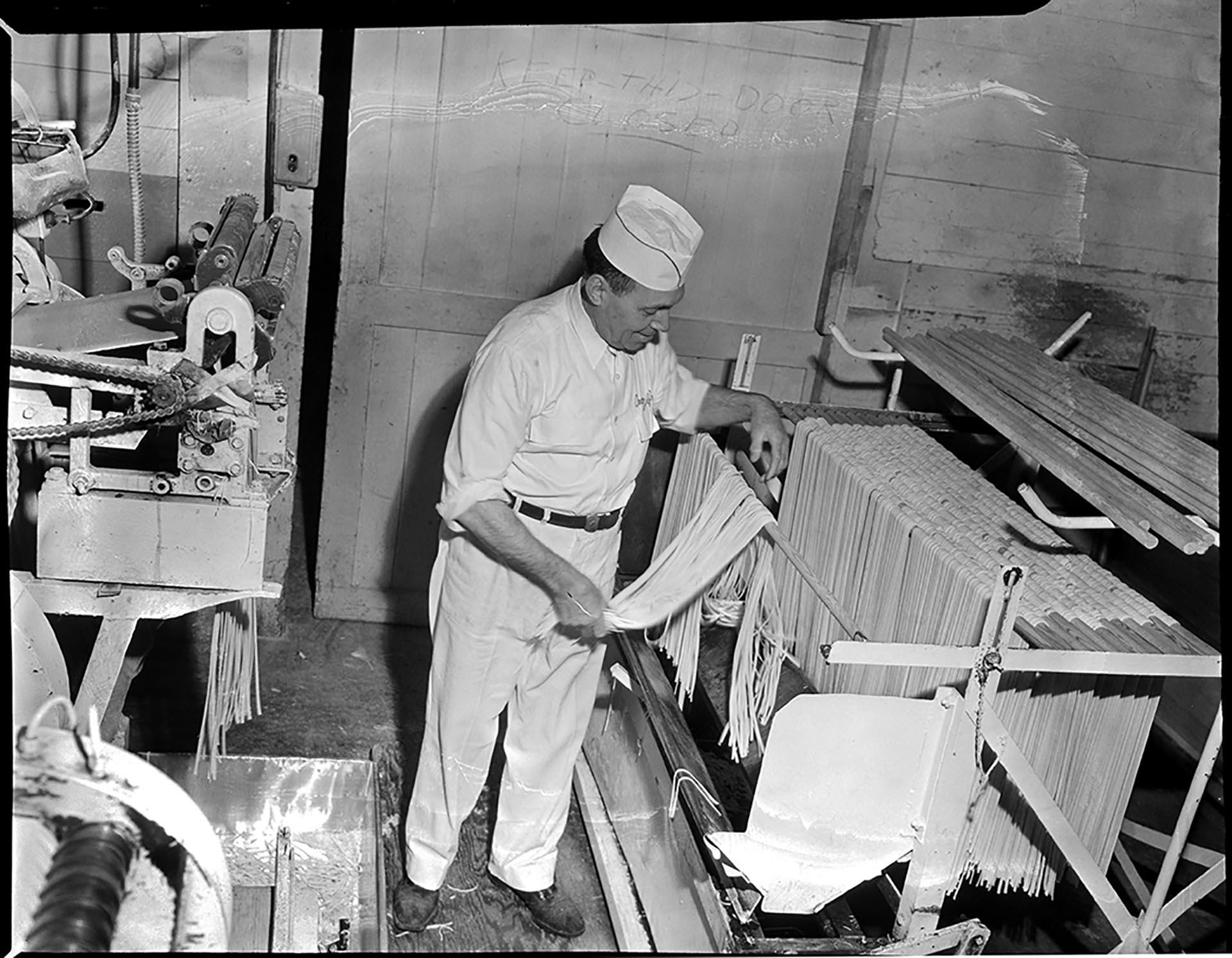 Image of Man hanging noodles on drying rack at Mission Macaroni Co., Seattle, January 1952