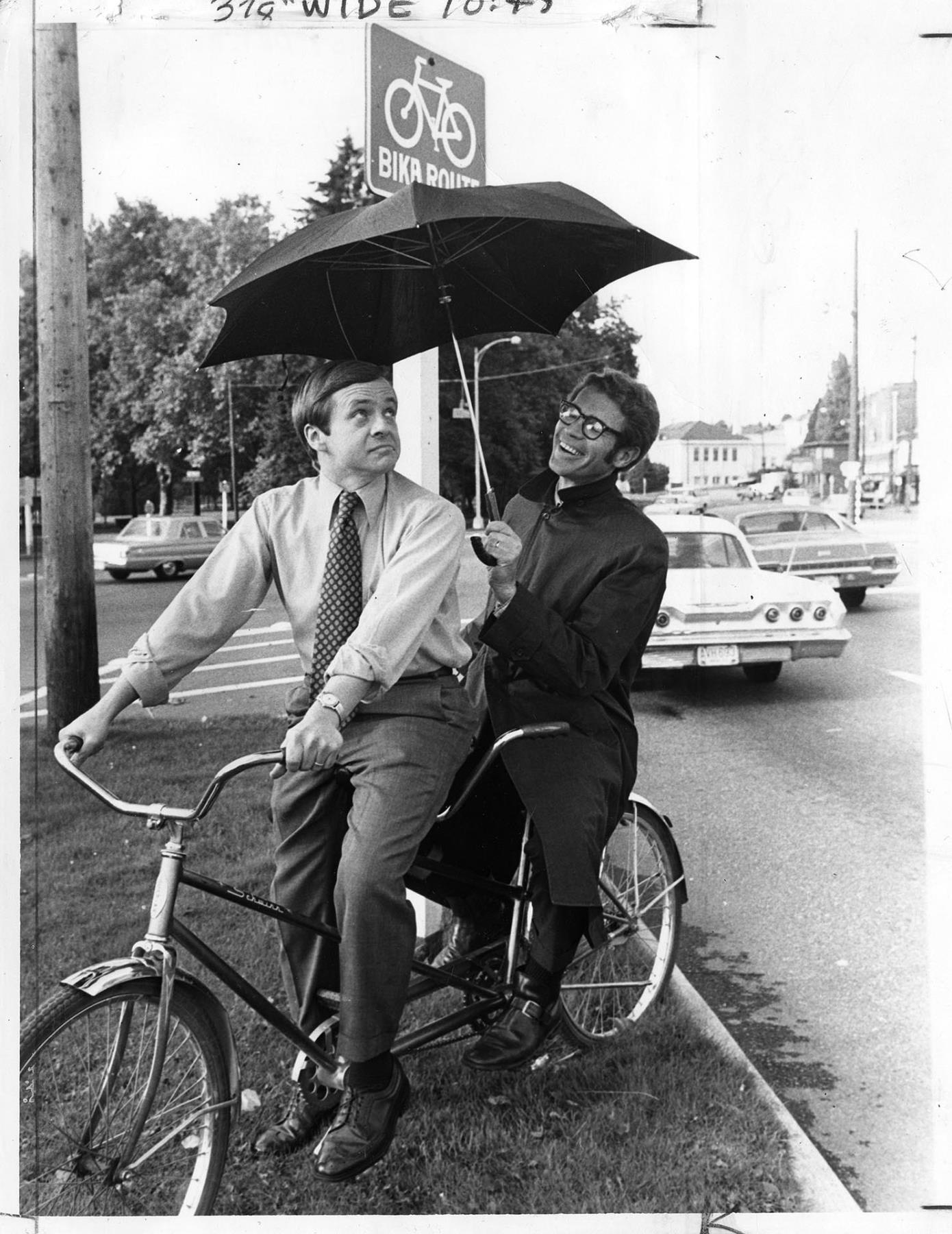 Image of TV weathermen on tandem bike, Seattle, October 13, 1971
