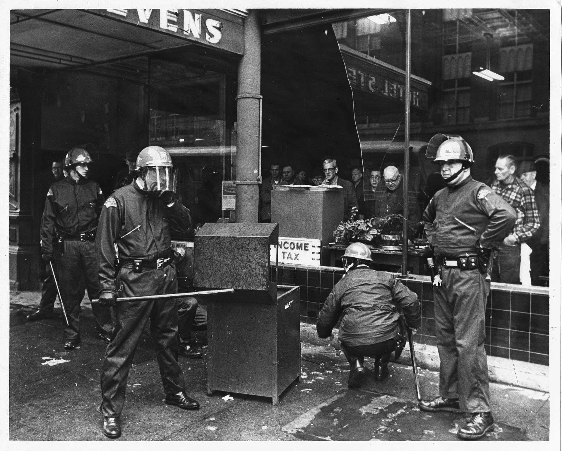 Image of Police examining broken glass outside Hotel Stevens after violent protests, Seattle, February 17, 1970