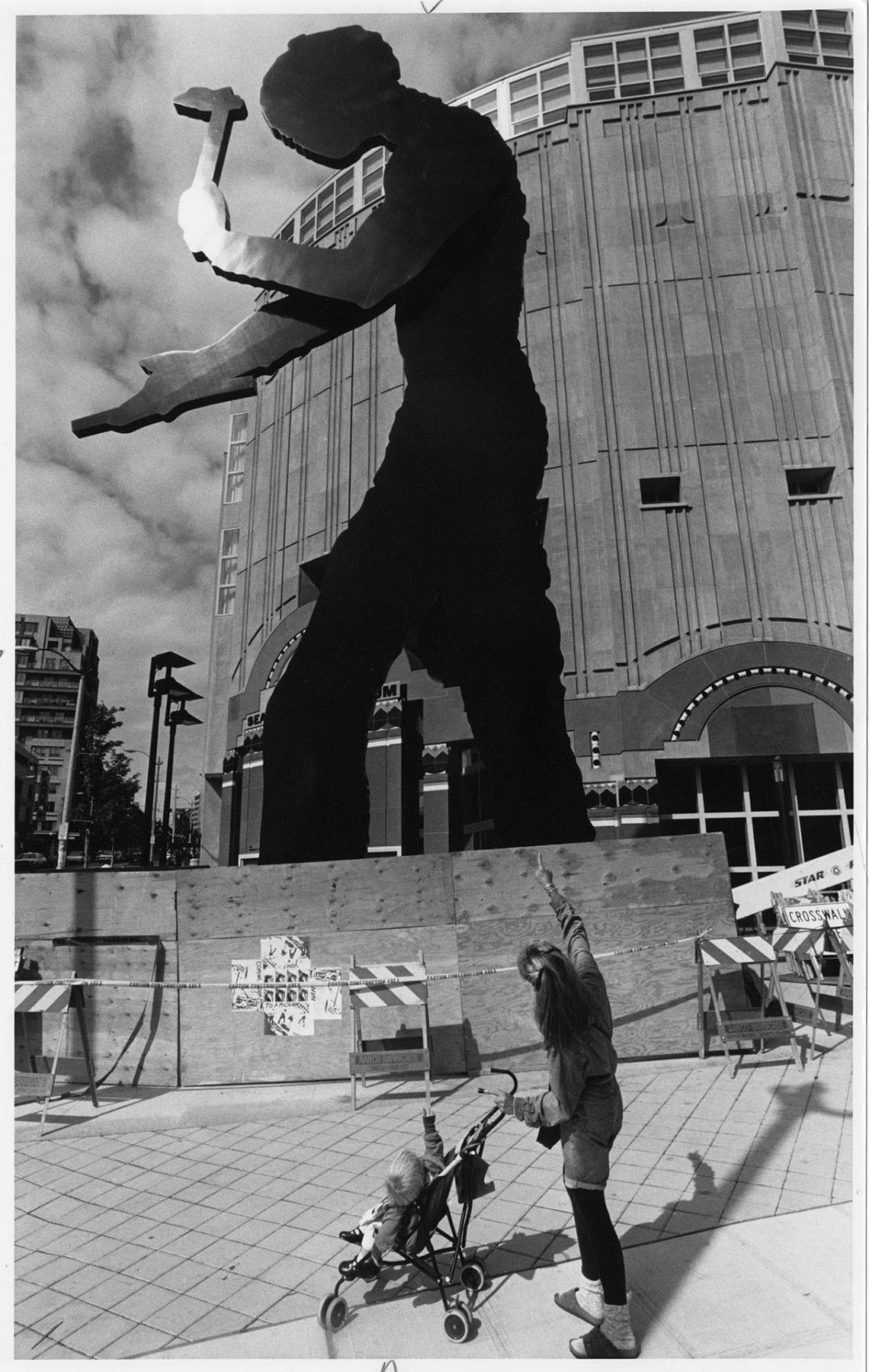 Image of Mother and child looking at Hammering Man in front of SAM, September 13, 1992