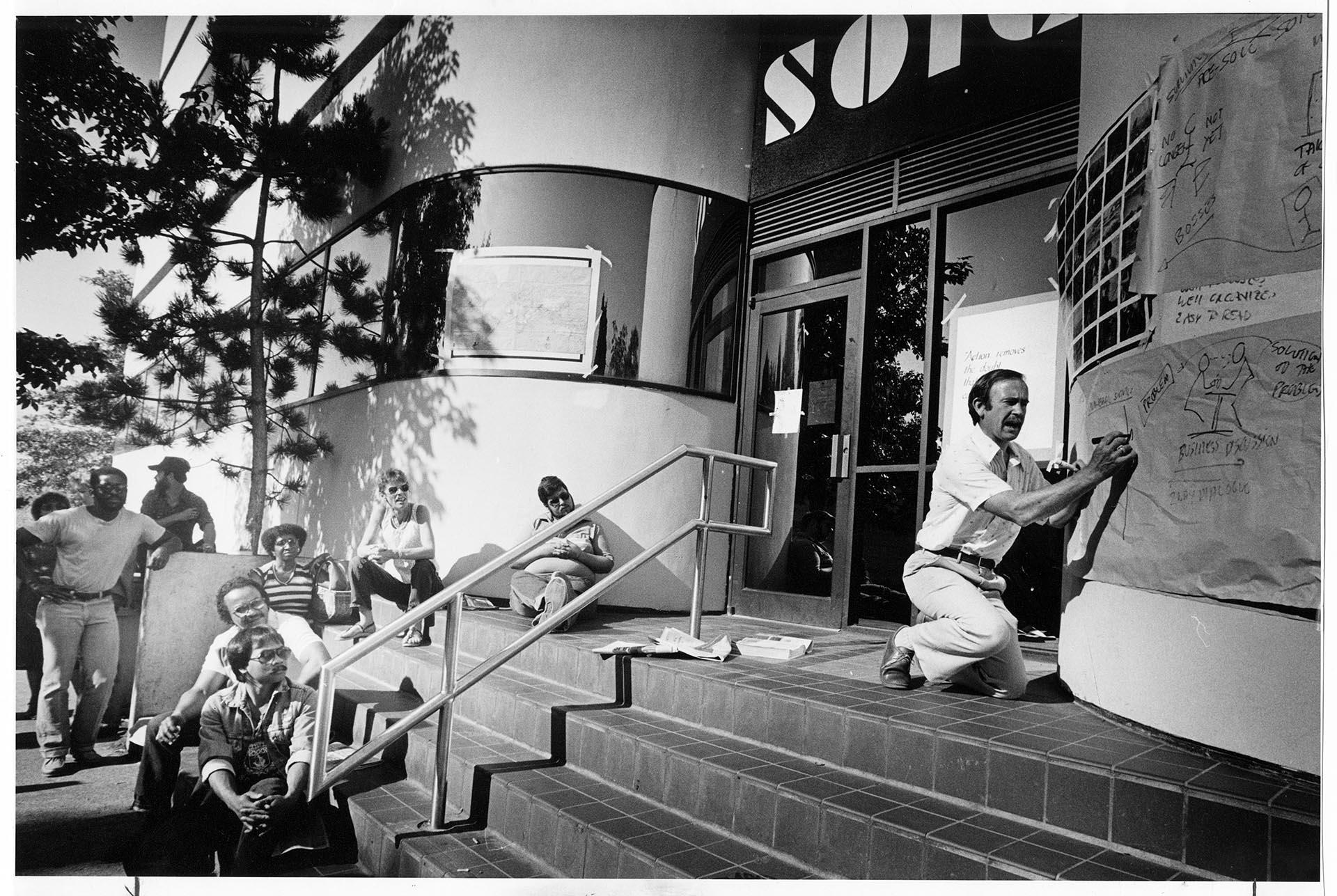 Image of Teacher and class on steps of closed SOIC building, August 1986