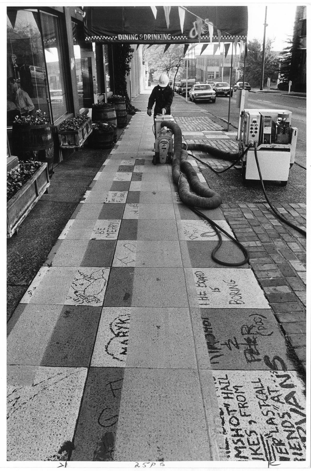 Image of Man removing sidewalk paint outside Duke's restaurant, Seattle, October 14, 1986