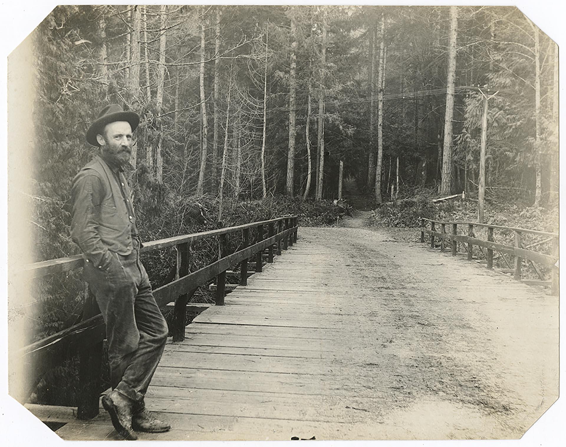 Image of Emil Schanno standing on bridge near Alki Point, Seattle, 1890