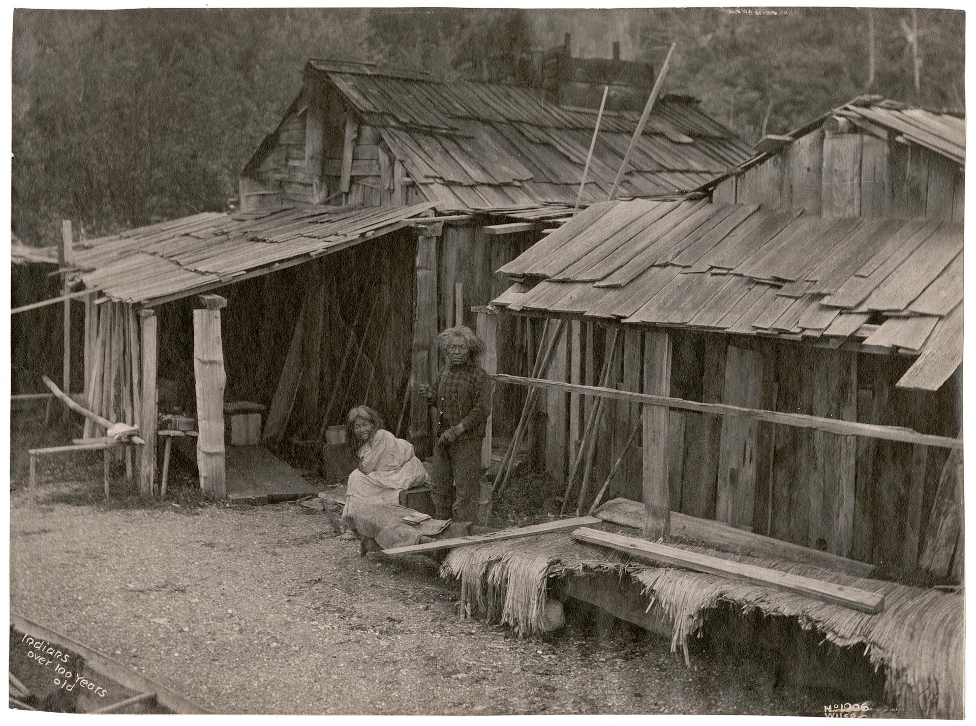 Image of Native American couple posing outside of wooden shack, Seattle, circa 1900