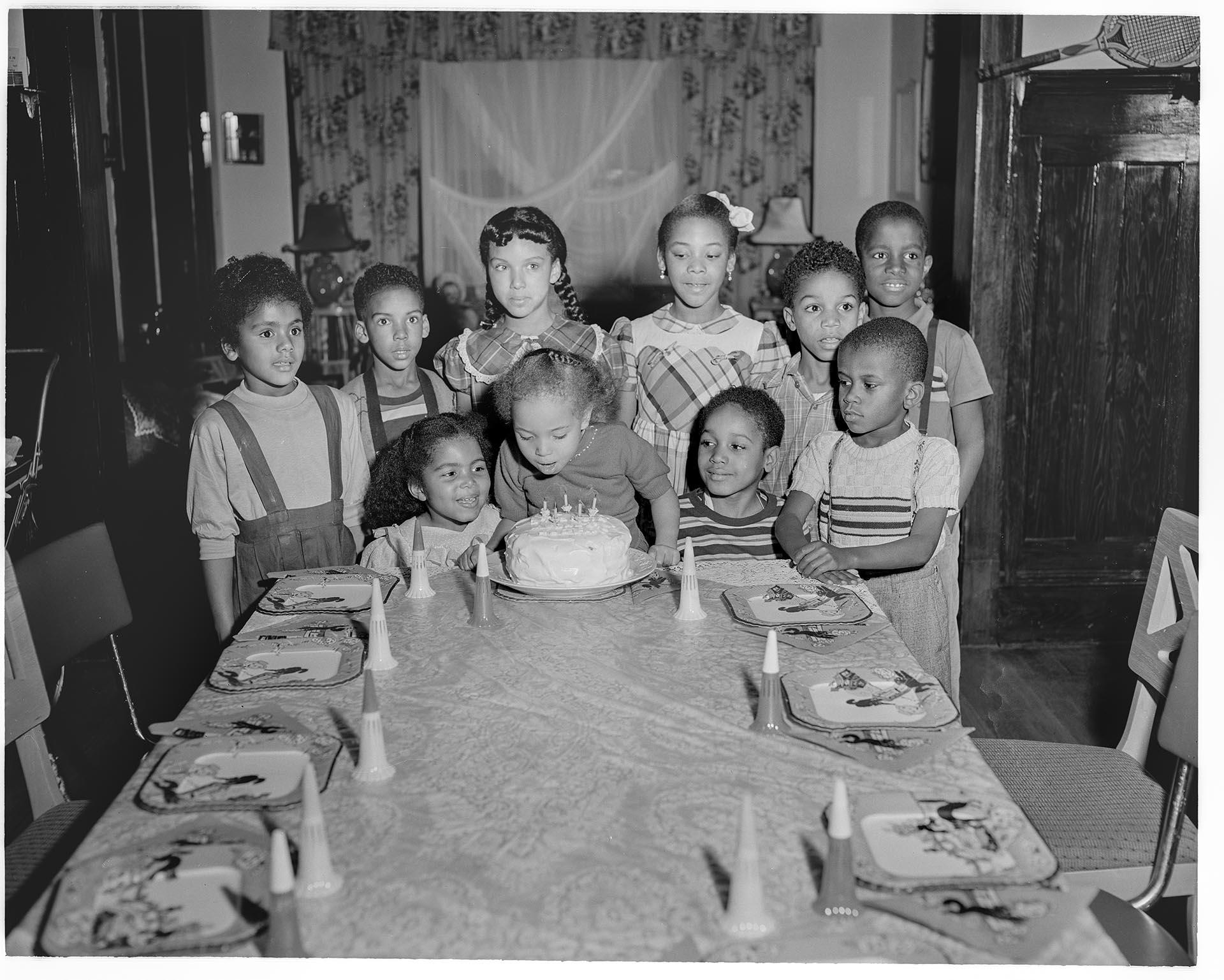 Image of Birthday girl blowing out candles at party, Seattle, circa 1953