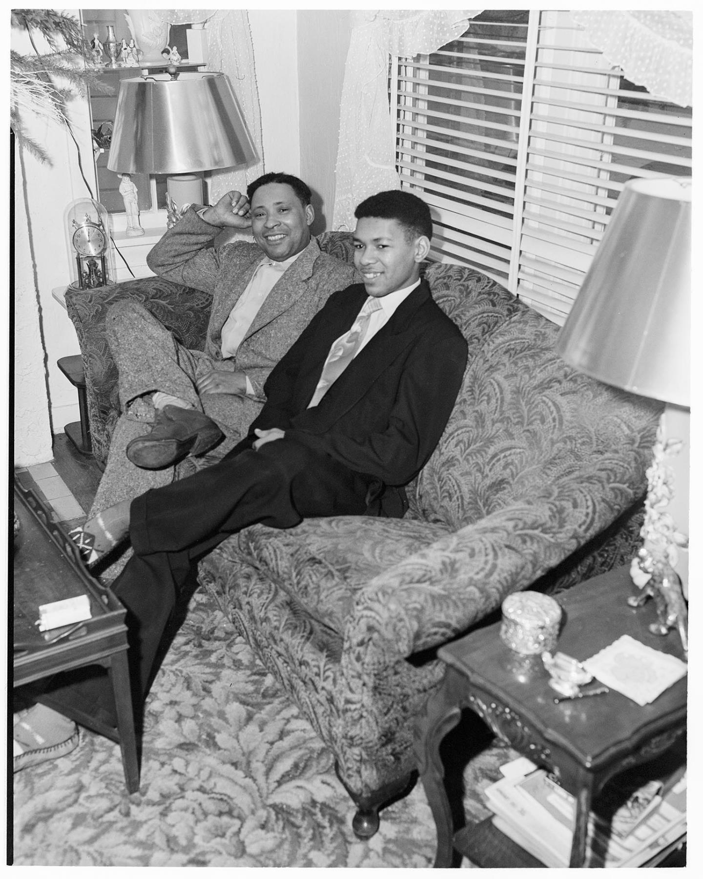 Image of Charlie Taylor, Sr. and his son sitting on couch, Seattle, circa 1953