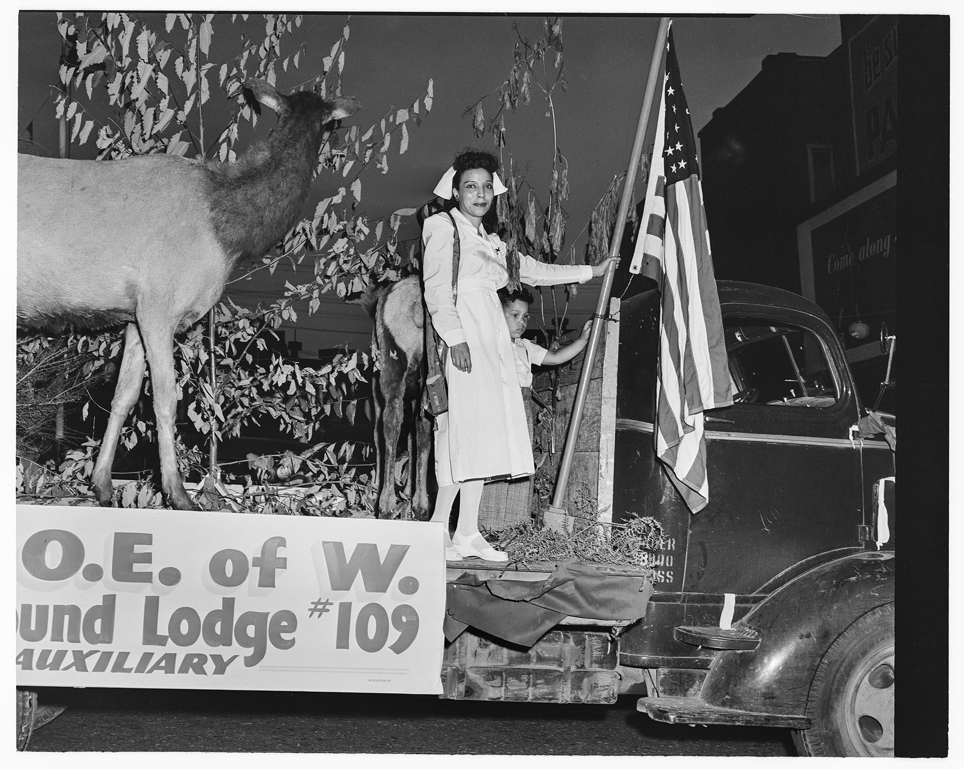 Image of Woman and boy standing on Elks parade float, Seattle, April  9, 1950