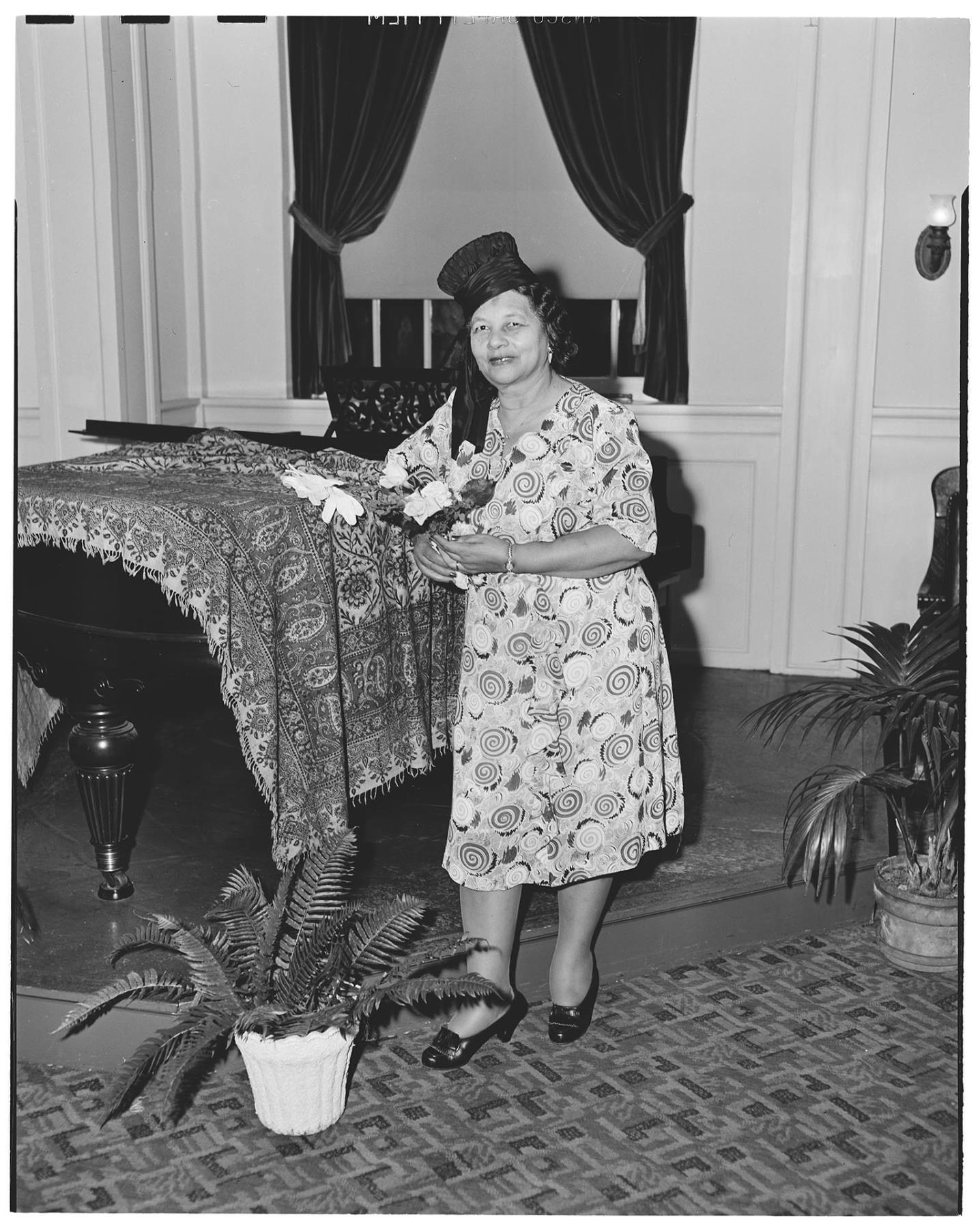 Image of NACWC convention delegate posing near piano, Seattle, August 1948