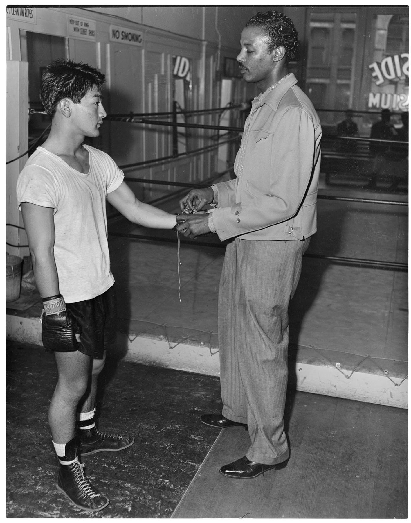 Image of Bill Ross lacing young boxer's gloves, Seattle, circa 1953