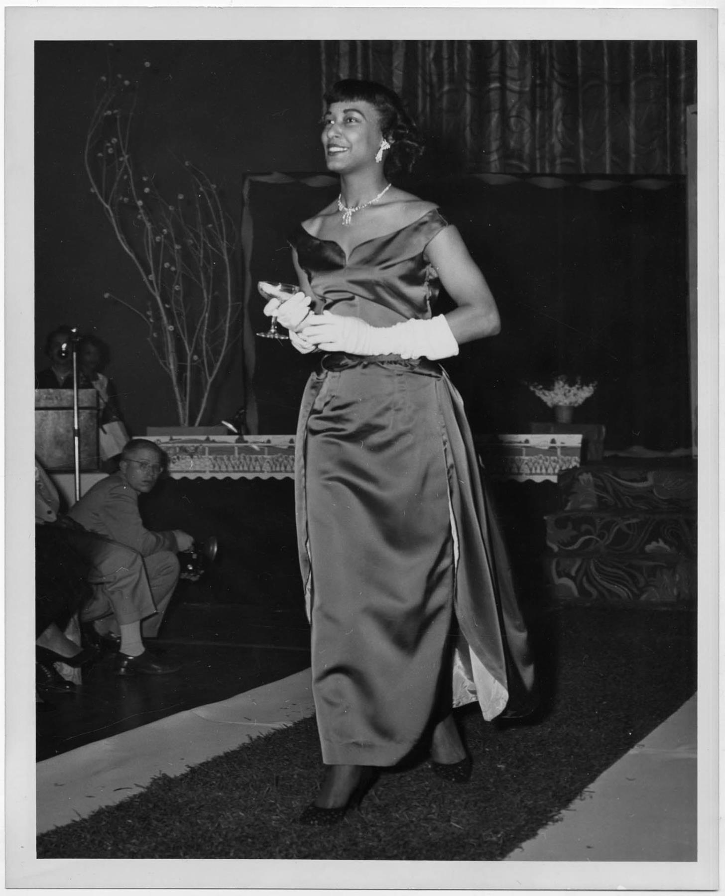Image of Woman modeling evening dress at a fashion show, circa 1955