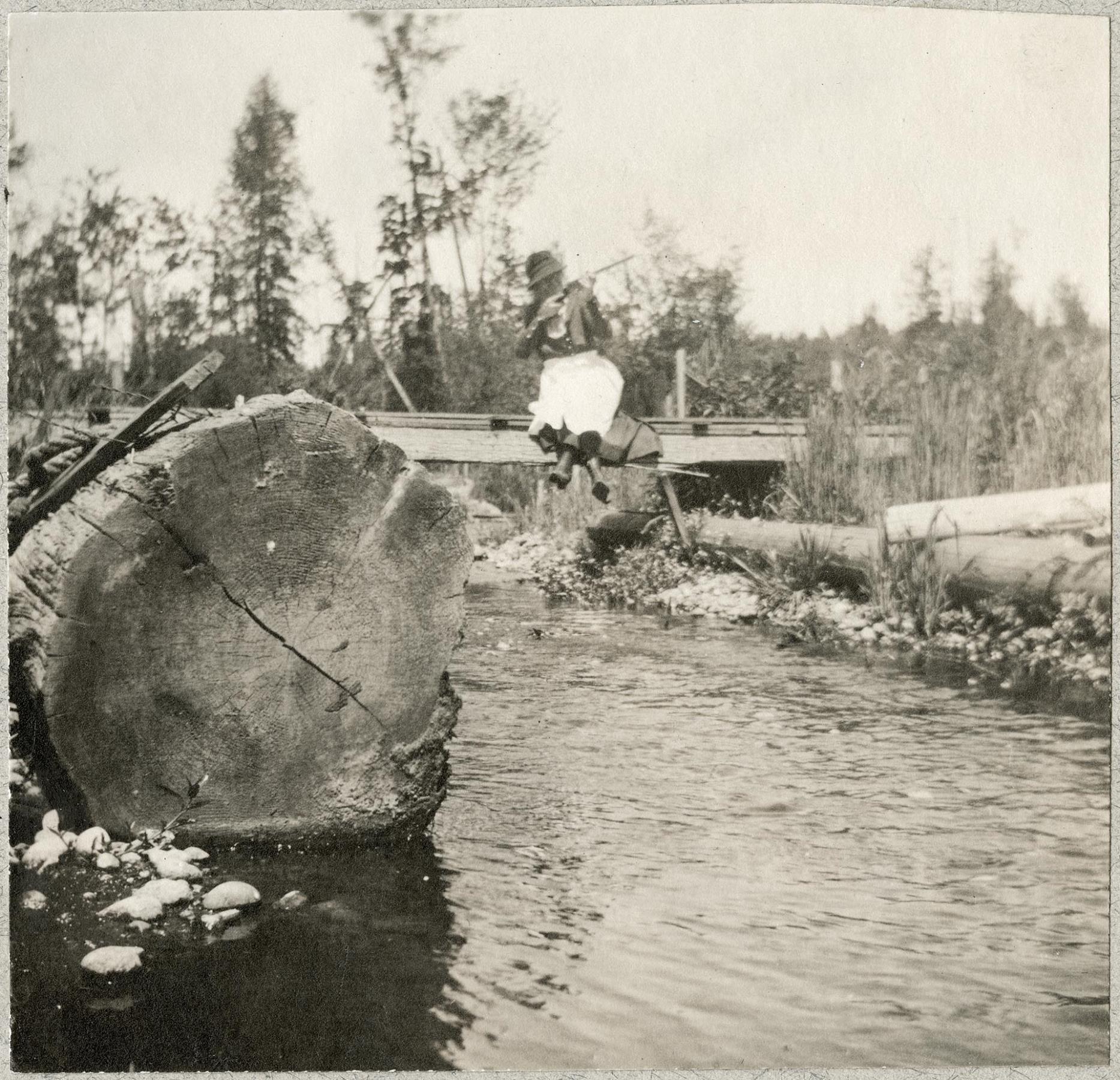 Image of Woman sitting on bridge over Ravenna Creek, Seattle, 1910