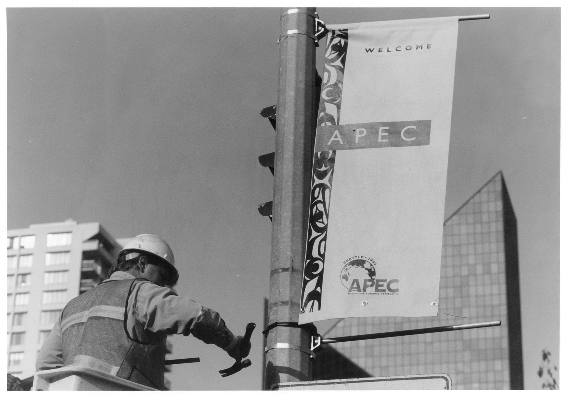 Image of Worker attaching welcome banner to post prior to APEC conference, Seattle, November 1993