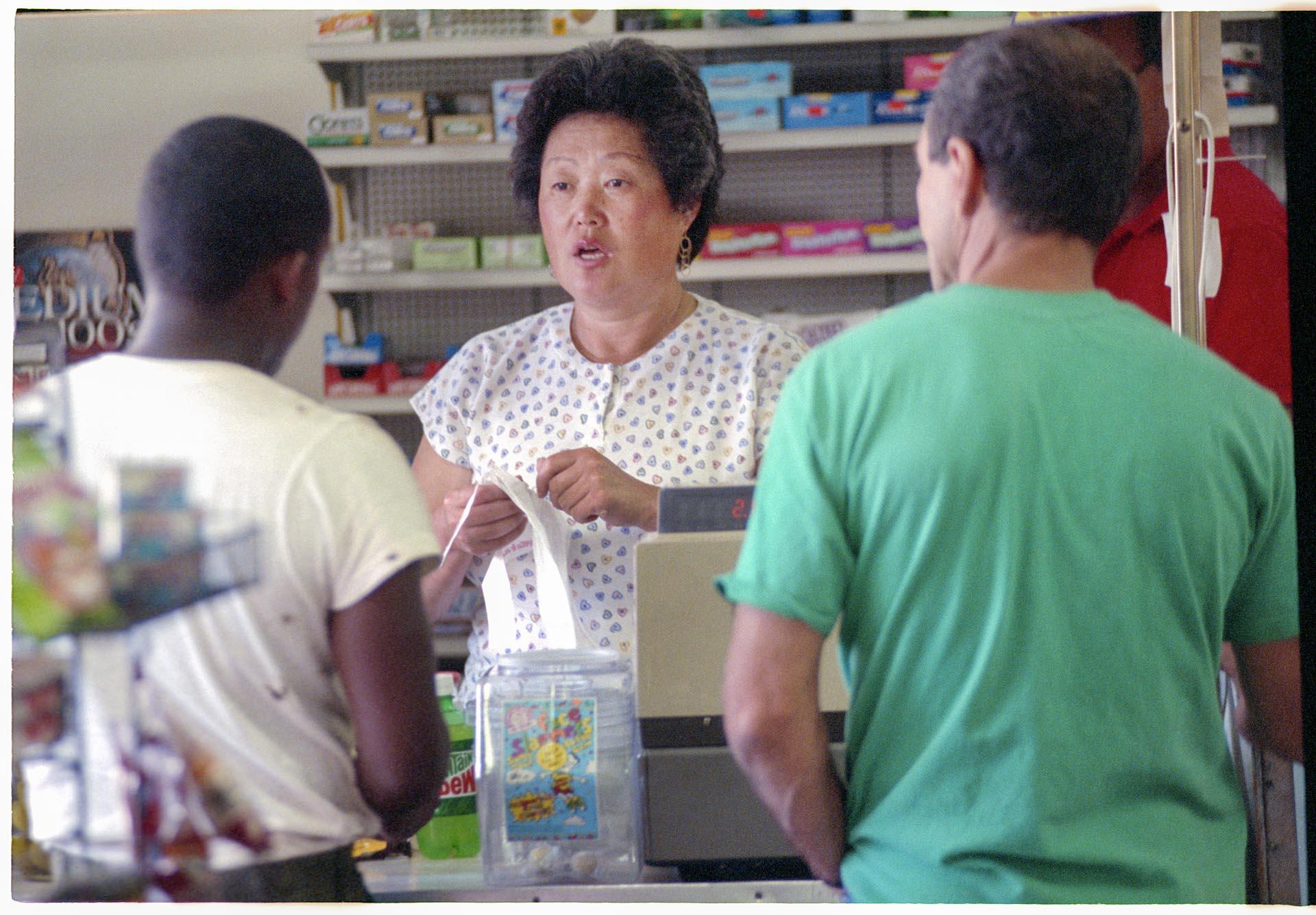 Image of Grace Chung with customers at Jeff Mart grocery store, Seattle, September 30, 1992