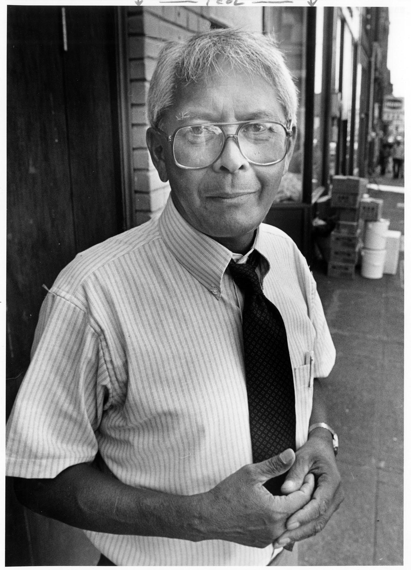 Image of Bob Santos standing on sidewalk in Chinatown - International District, Seattle, July 18, 1986