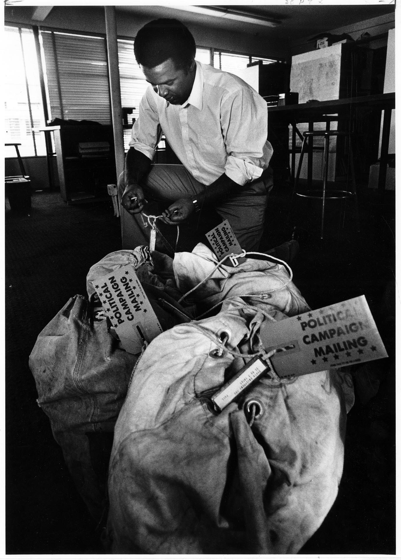 Image of Ron Sims fastening tags to sacks of campaign mail, Seattle, September 13, 1985