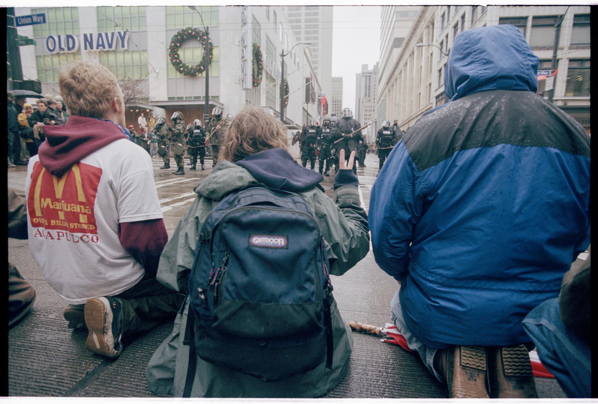 Image of Kneeling demonstrators facing police line at WTO protest, Seattle, December 1, 1999