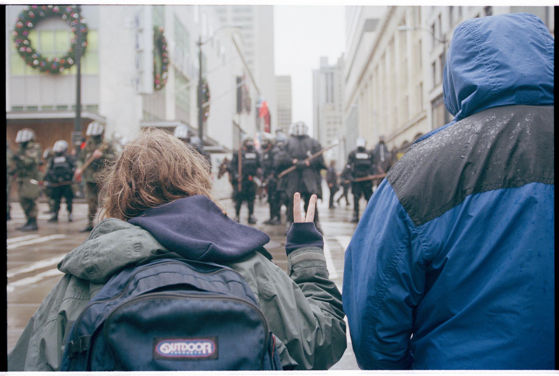 Image of Kneeling demonstrators facing police line at WTO protest, Seattle, December 1, 1999