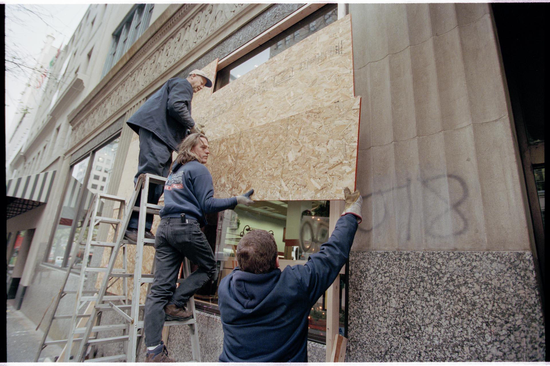 Image of Workers covering store windows prior to WTO protests, Seattle, December 3, 1999