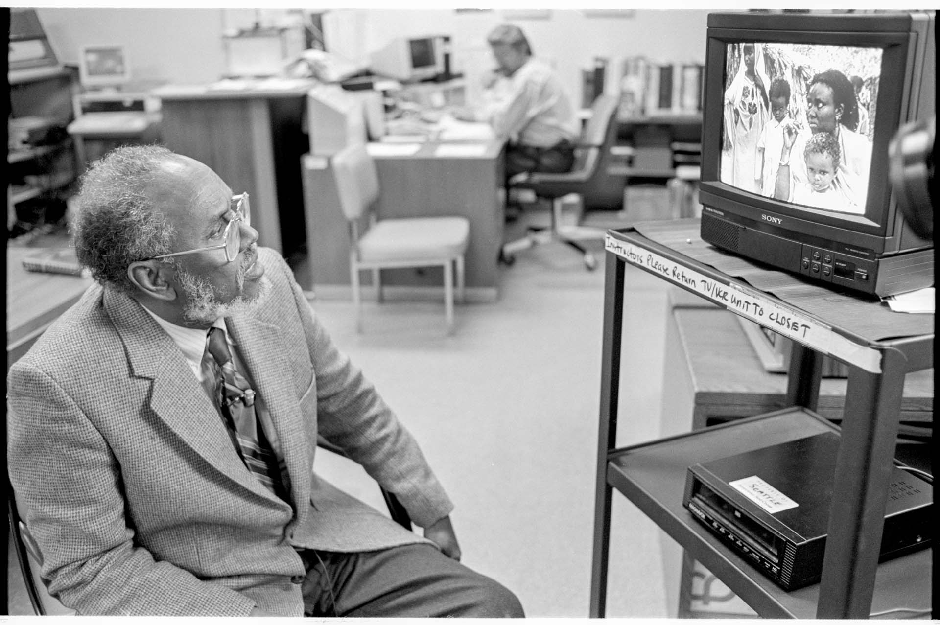 Image of Ahmed Isse looking at photographs at Red Cross headquarters, Seattle, December 28, 1992