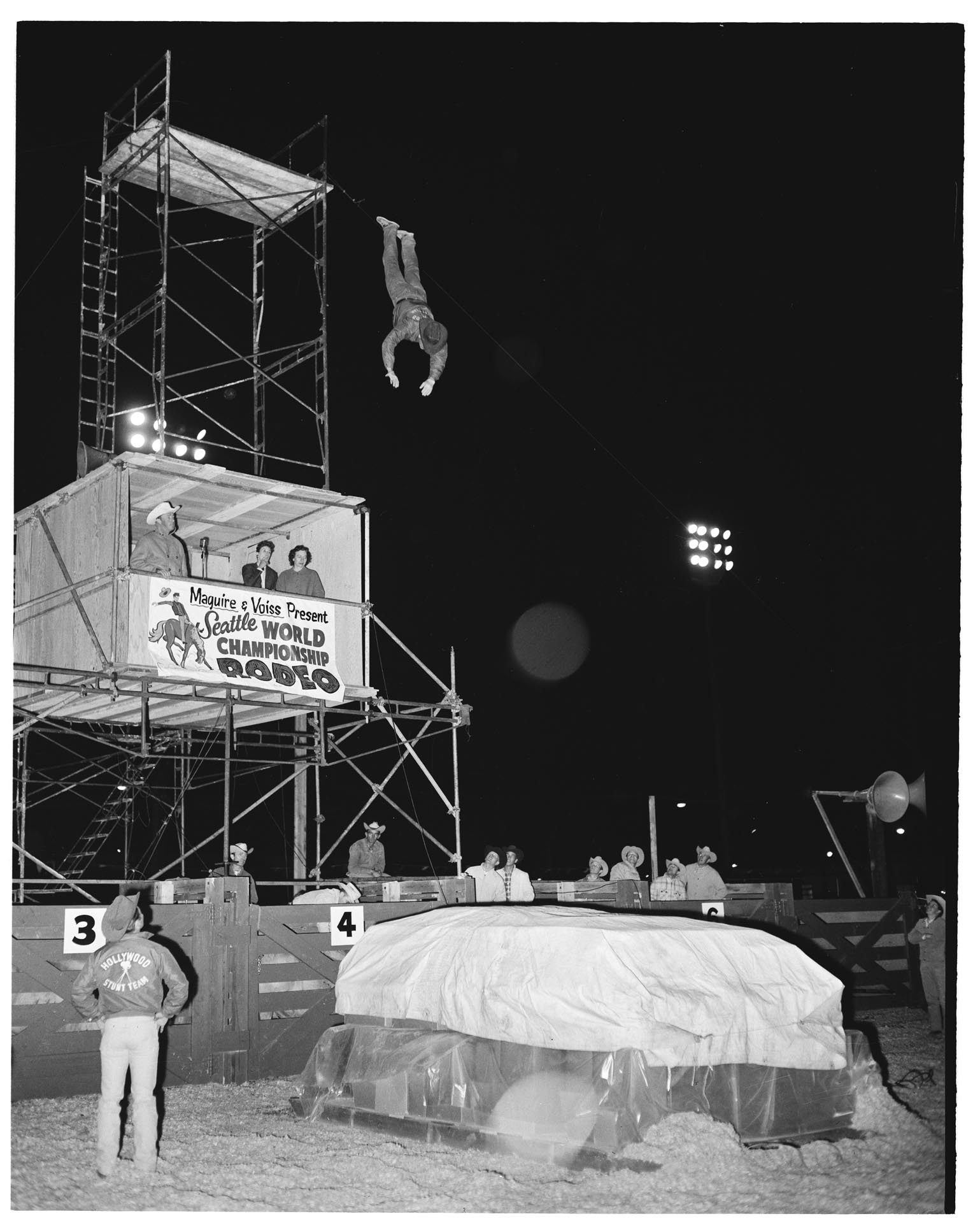 Image of Stunt cowboy jumping off of  platform at rodeo, 1962