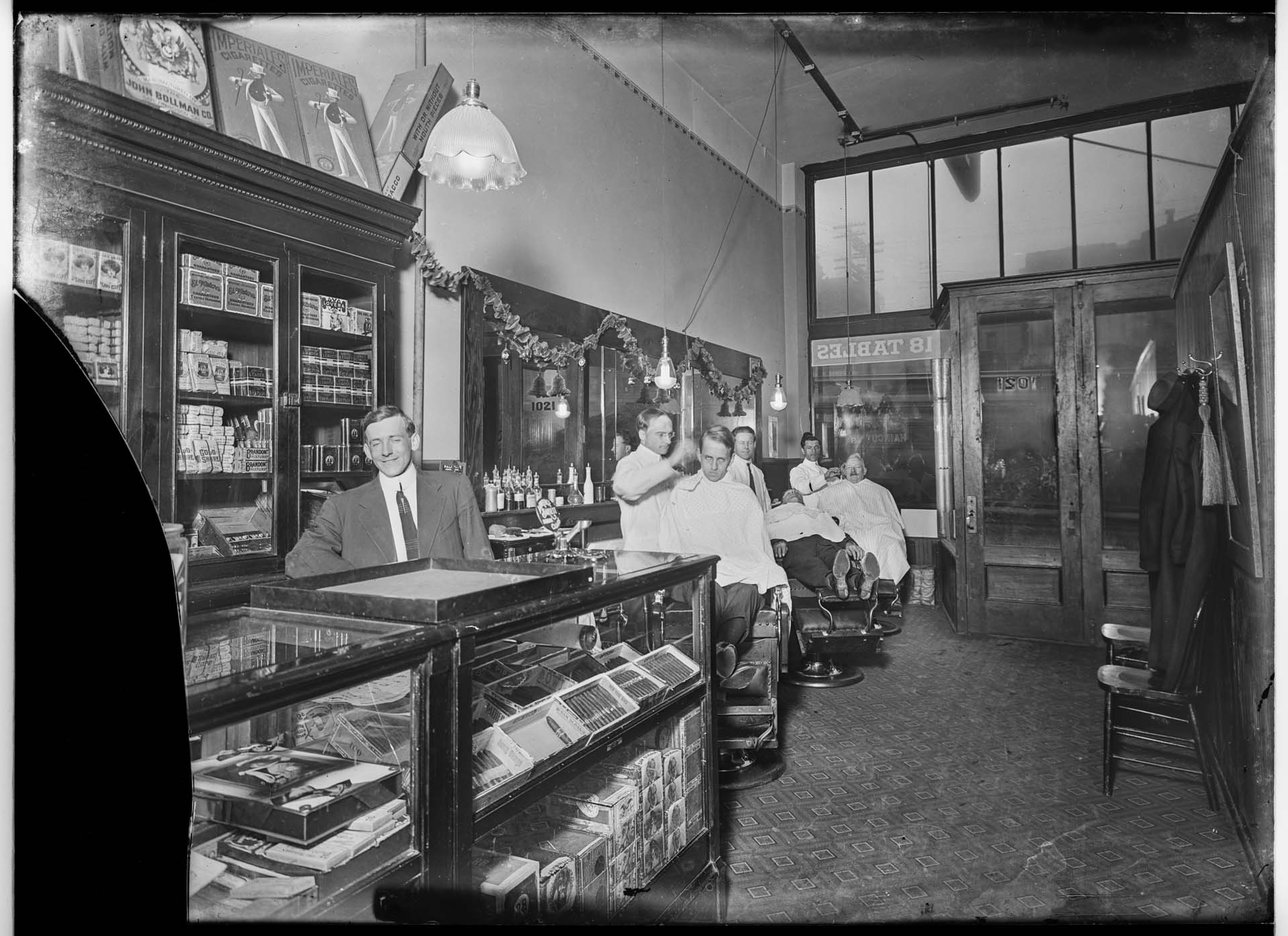 Image of Barbers with customers inside barbershop. Seattle, 1912