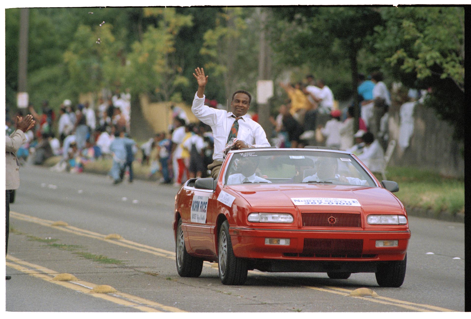 Image of Norm Rice waving from car at Mardi Gras parade, July 25, 1993