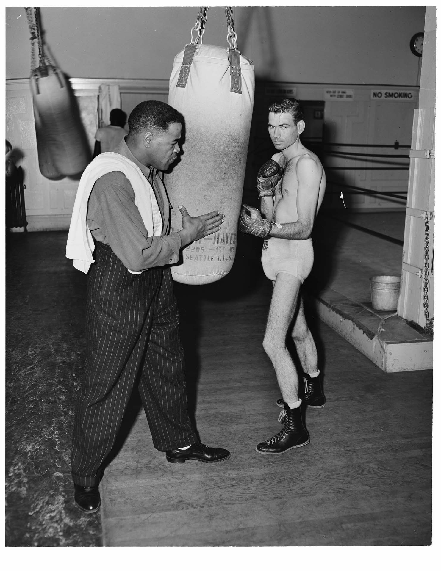 Image of Trainer and boxer in gym with heavy bag, Seattle, circa 1952