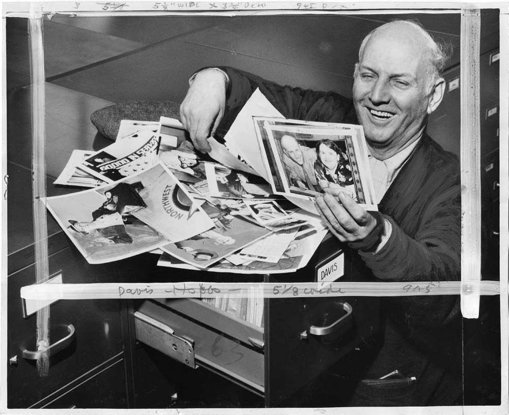 Image of Jeff Davis looking at newspaper photos of himself, Seattle, May 1952