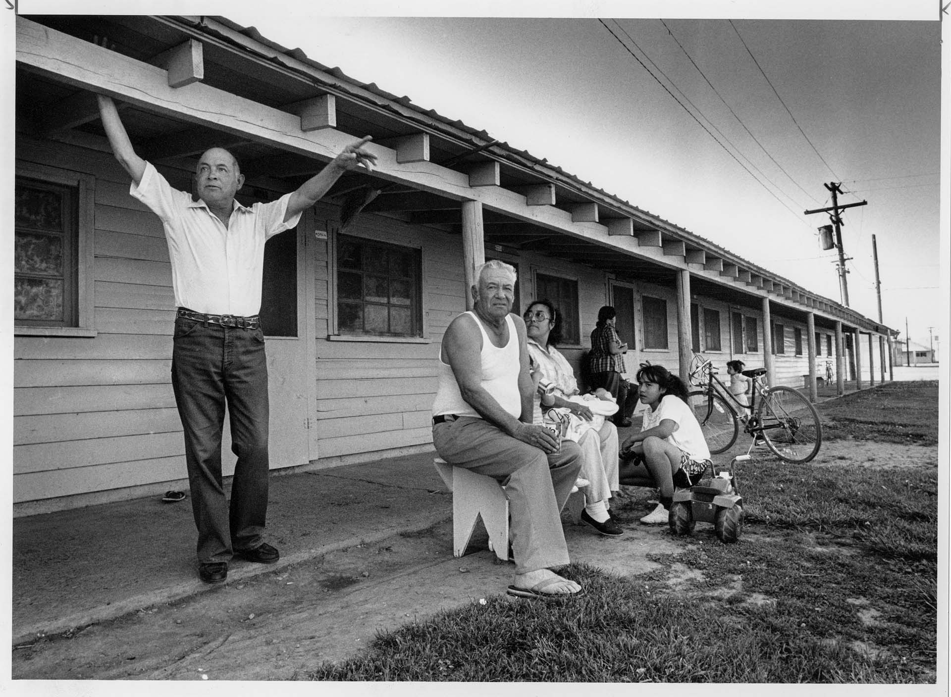 Image of Joe Garza and others outside worker housing at Golding Farms, Yakima Valley, May 1989