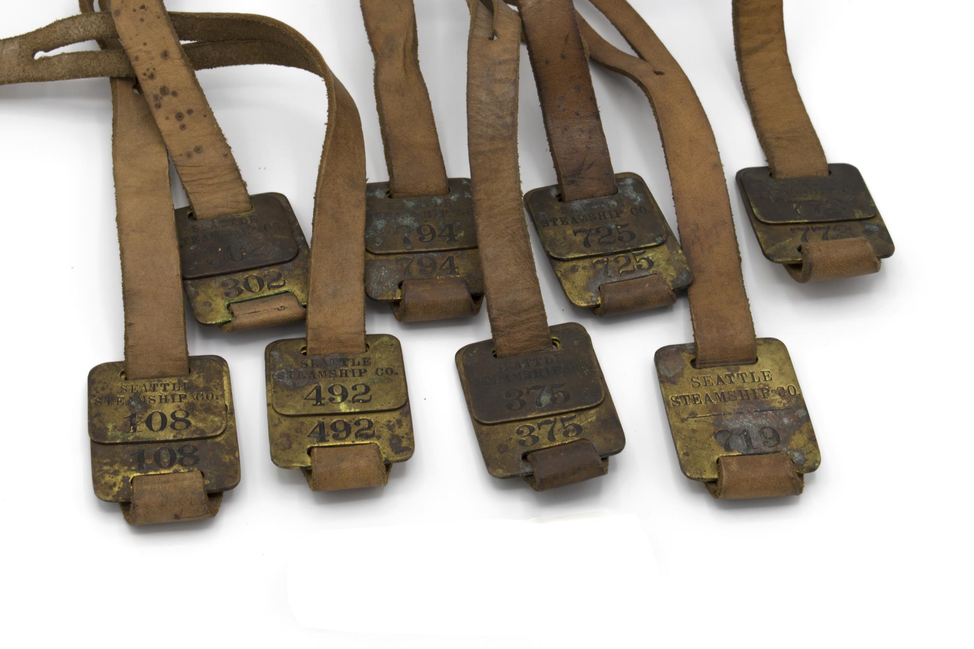 Image of Set of brass luggage claim check tags from Seattle Steamship Company, ca. 1900-1920