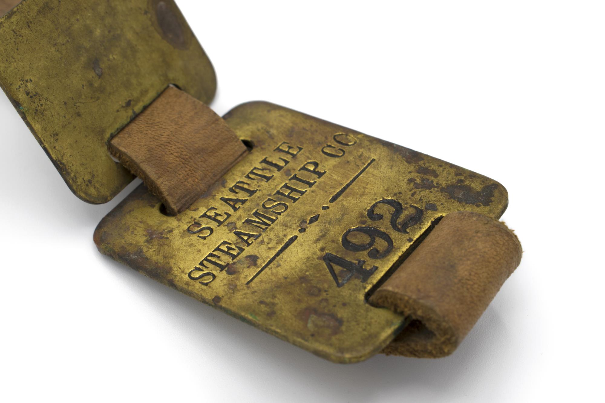 Image of Set of brass luggage claim check tags from Seattle Steamship Company, ca. 1900-1920