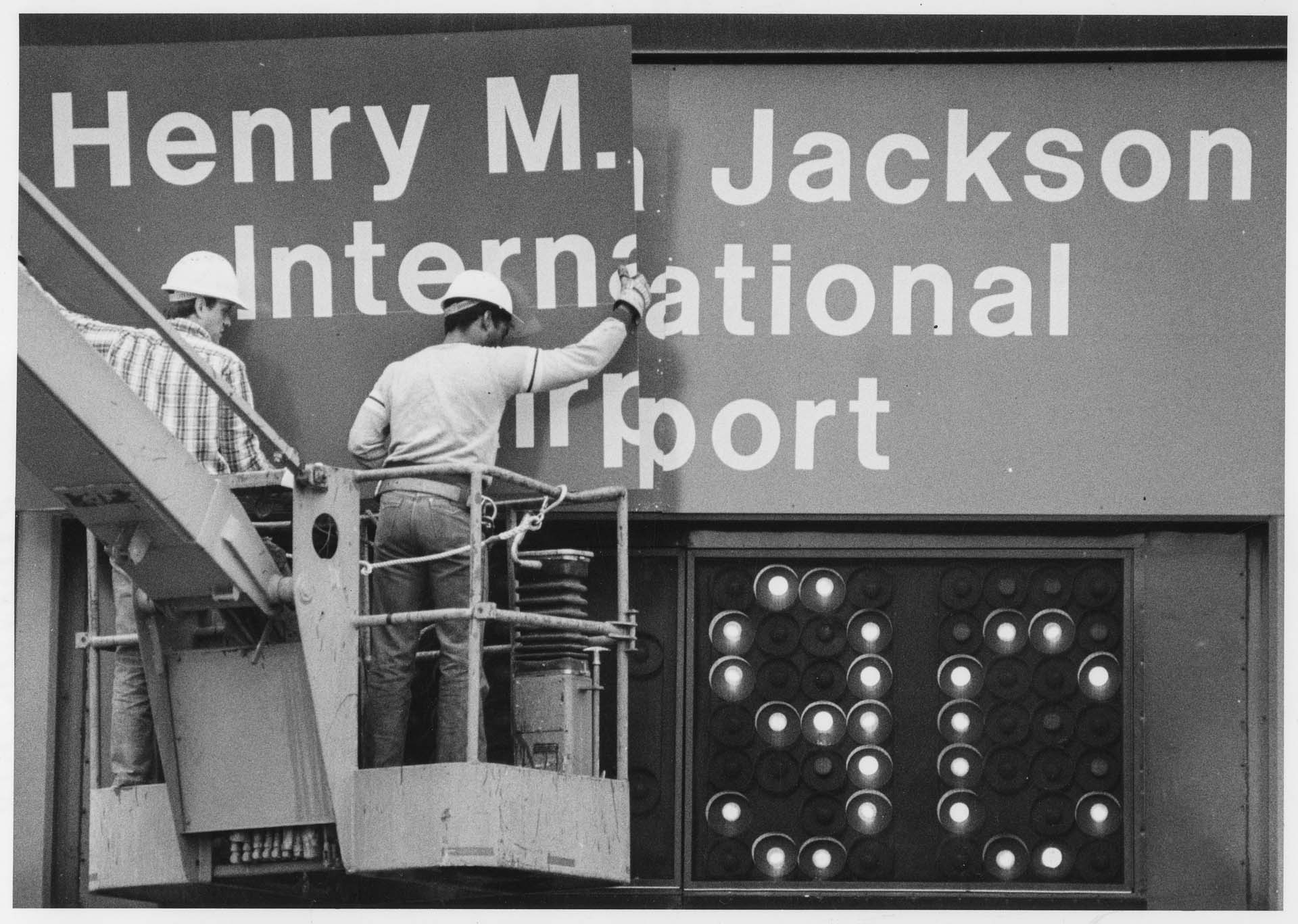 Image of Workers removing sign at SeaTac airport, March 1984