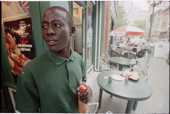 Image of William Deng holding a bottle of mango juice outside store, Seattle, 2001