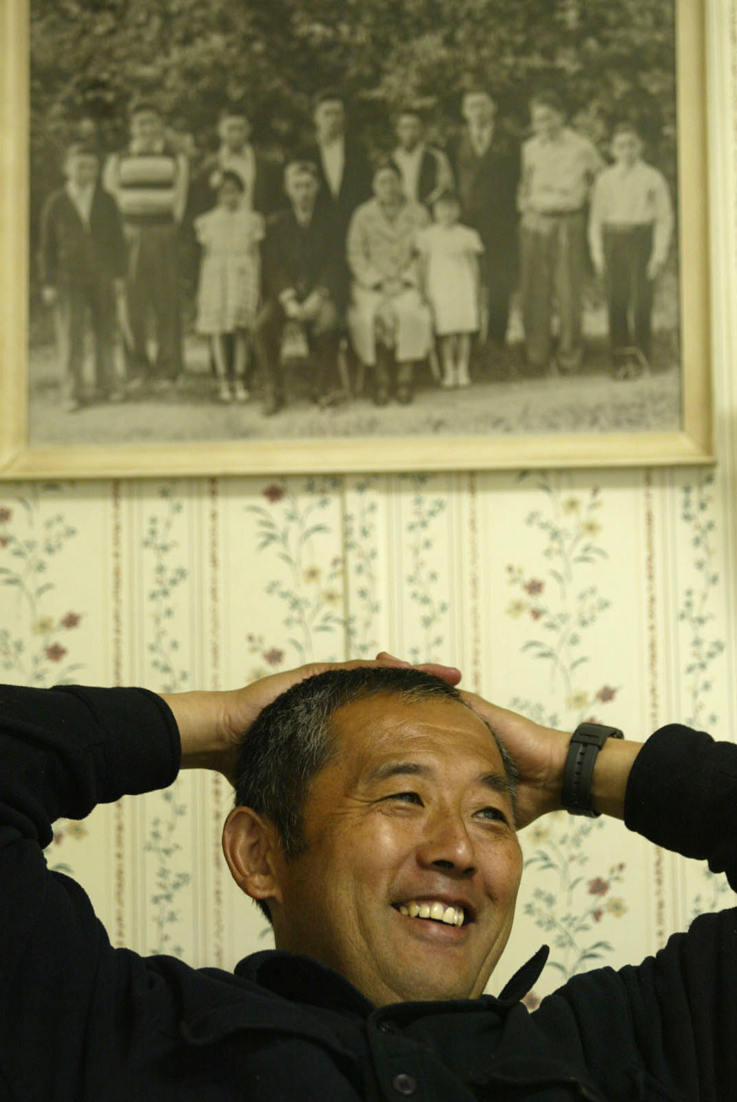 Image of Steve Sakuma with portrait of his grandparents and their children, Burlington, Washington, June 27, 2002
