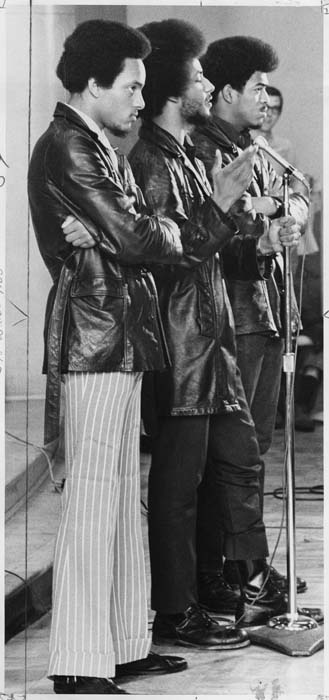 Image of Aaron Dixon, with bodyguards, speaking at rally at HUB Ballroom, Seattle, April 4, 1969