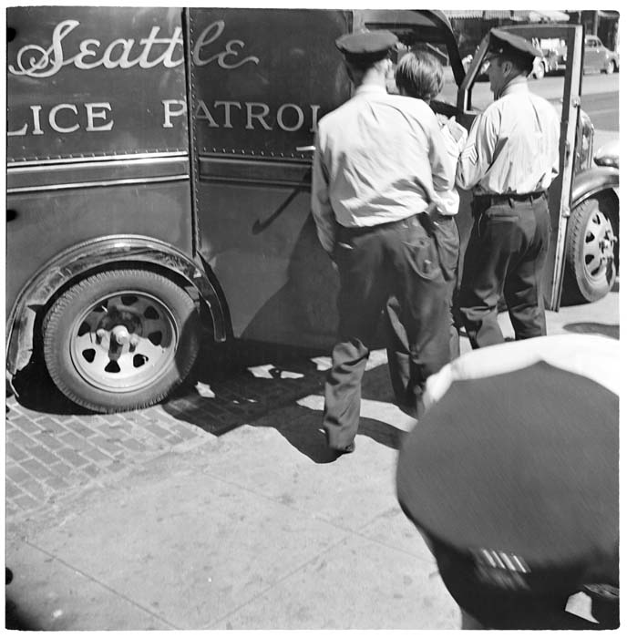 Image of Officers escorting man to police van, Seattle, circa 1940