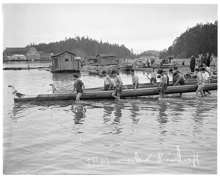 Image of Indigenous rowers carrying racing canoes into water, La Conner, November 29, 1941